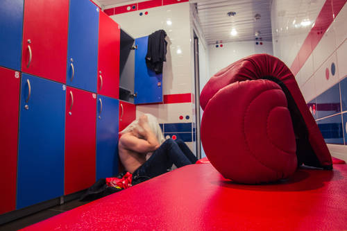 Tired man sitting on the floor in the locker room after finishing training
