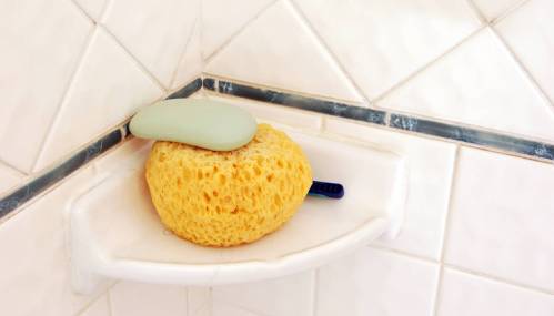 A yellow shower sponge in the corner of a shower