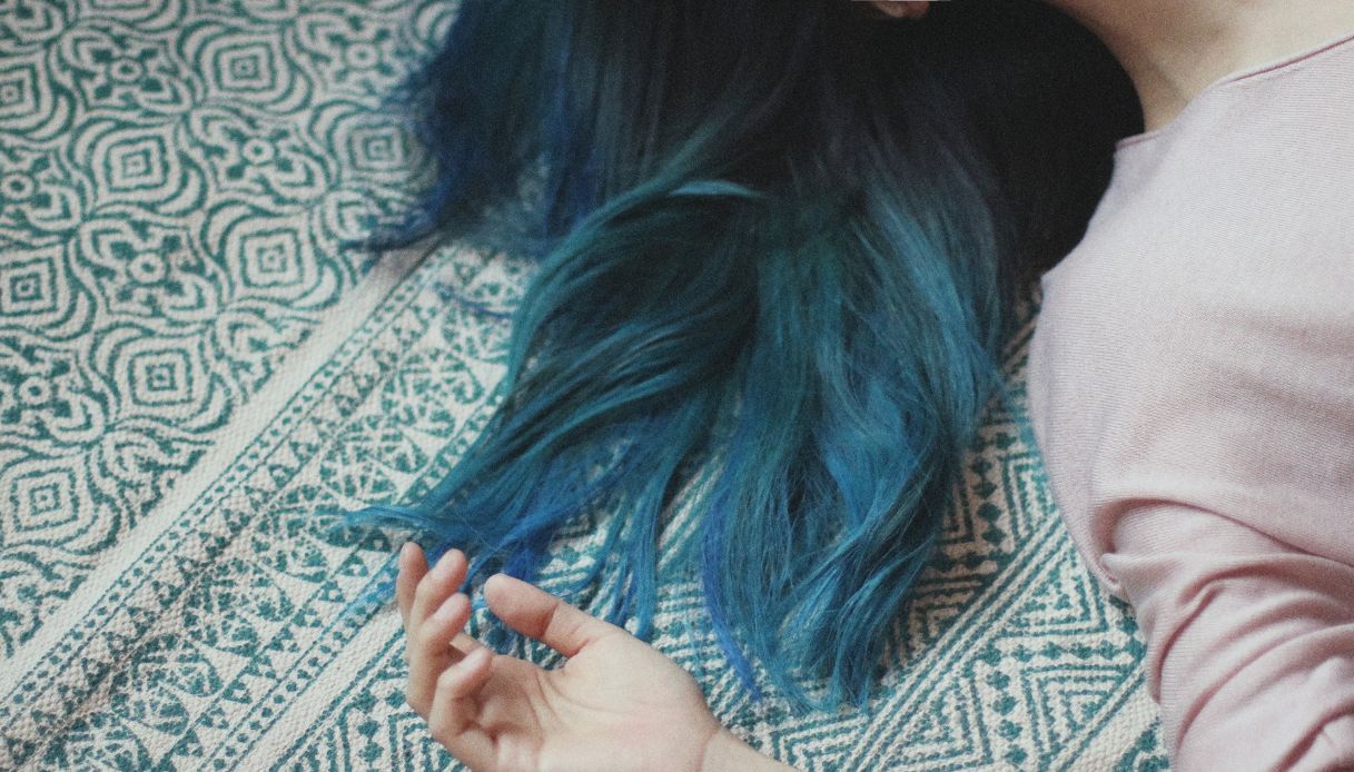 capelli blu petrolio e mano di donna distesa su tappeto