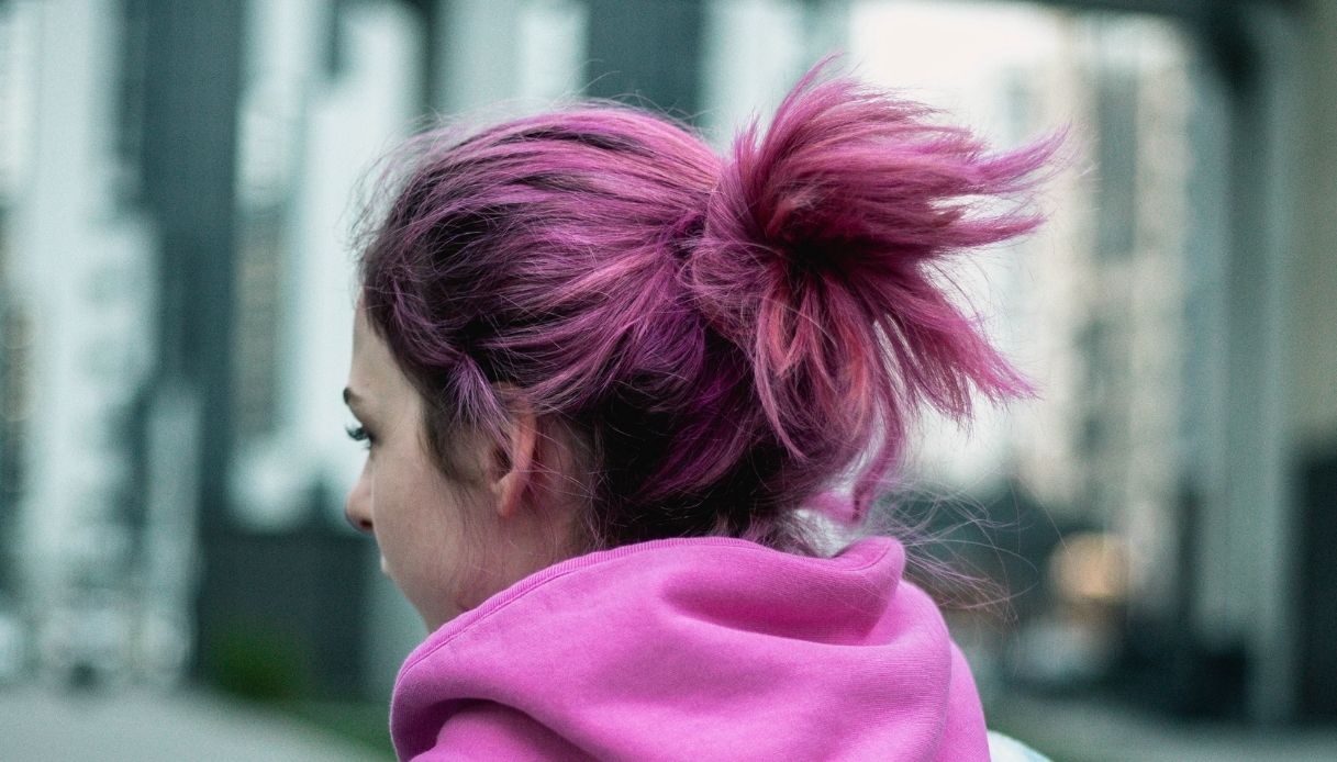 ragazza di spalle con capelli fucsia raccolti in un crocchia e felpa rosa
