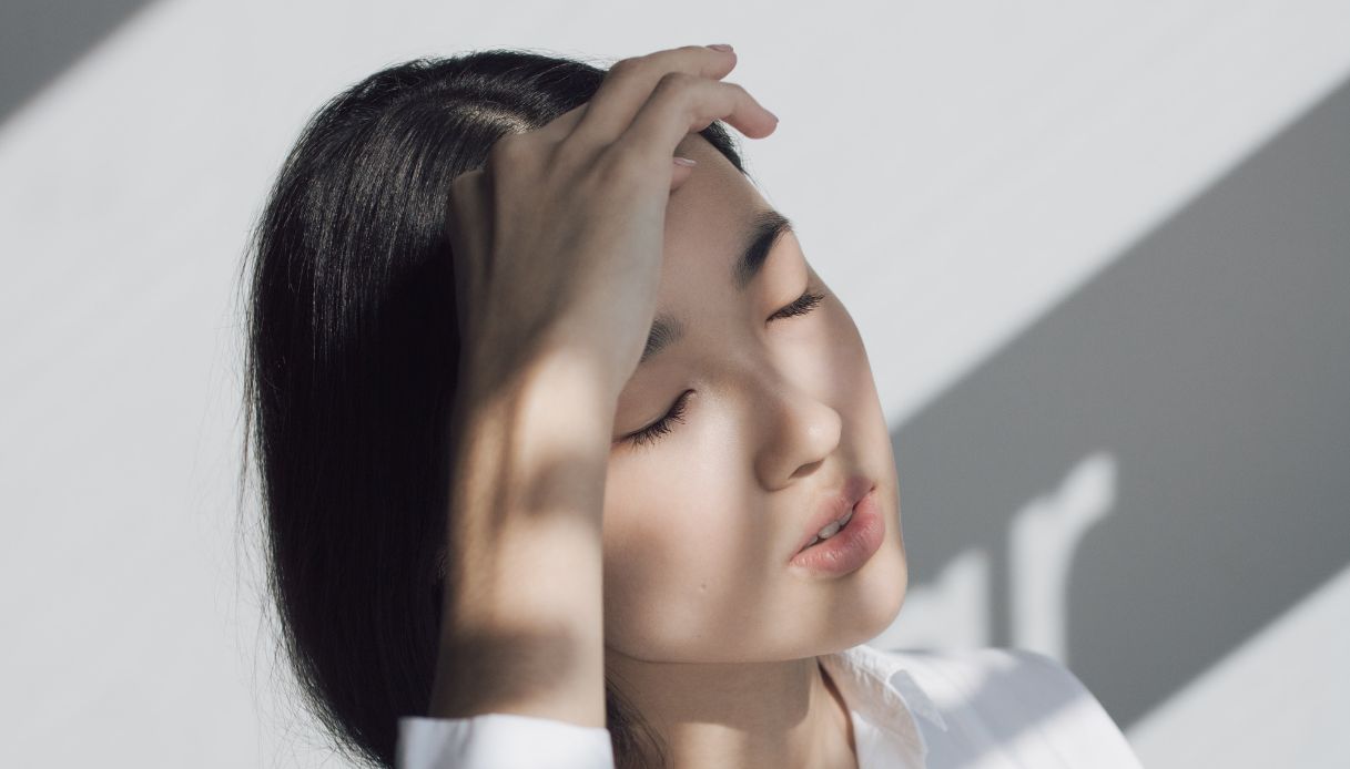 donna orientale si ripara gli occhi dai raggi del sole e ha capelli neri raccolti