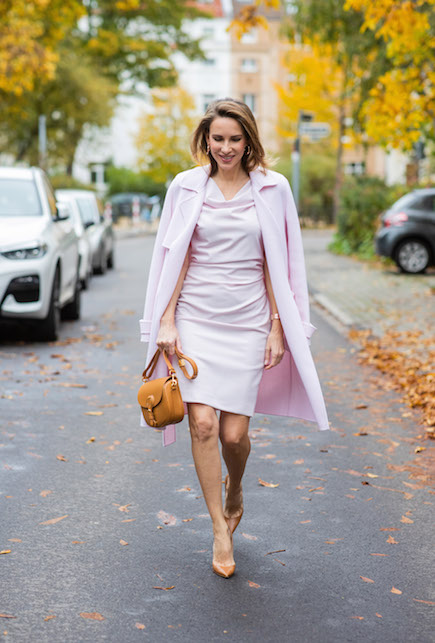 Modella con tubino e cappotto rosa, borsa e scarpe marroni