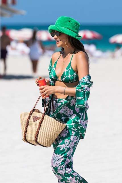 ragazza con costume e cappello verde in spiaggia e borsa di paglia