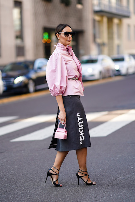 modella giacca e borsa colorata rosa, gonna nera e scarpe con il tacco