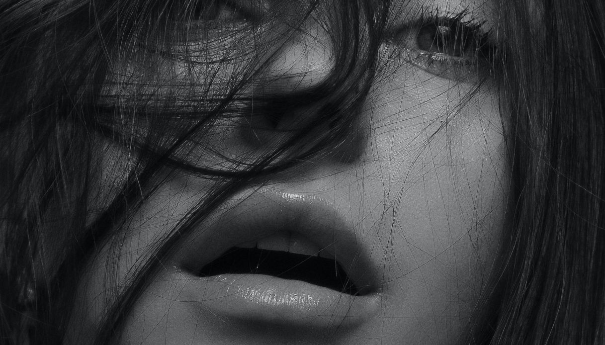 foto in bianco e nero di una donna con labbra carnose socchiuse e capelli sulla faccia