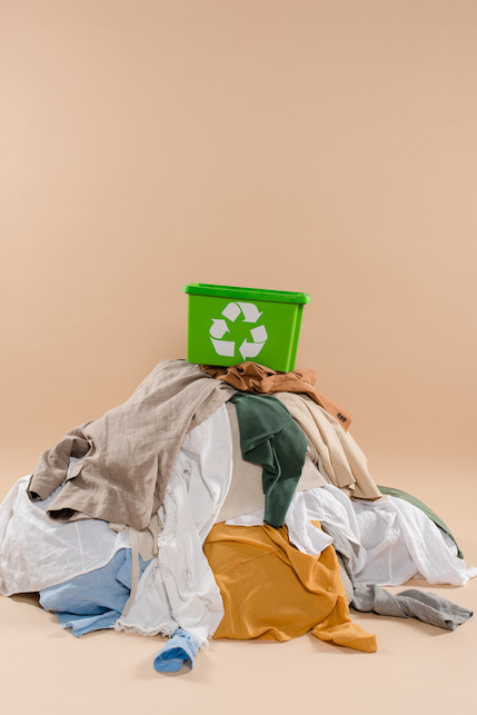 abiti usati di diversi colori con cestino per riciclo