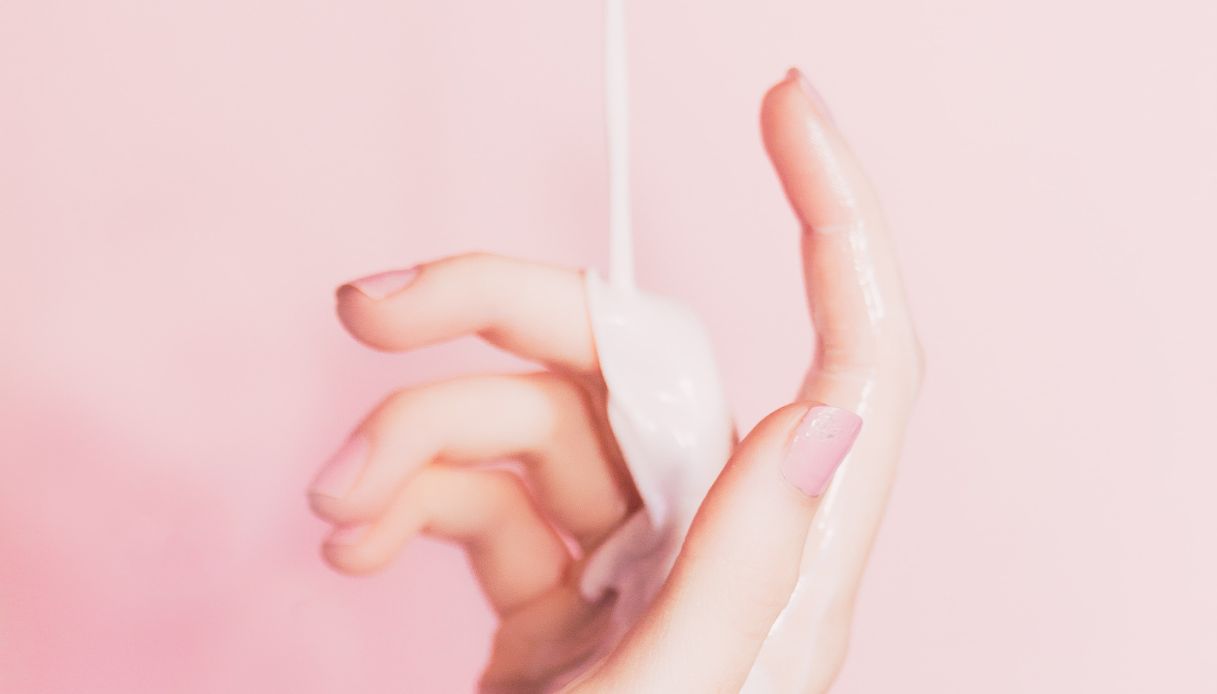 crema fluida cola su mano di donna con smalto rosa
