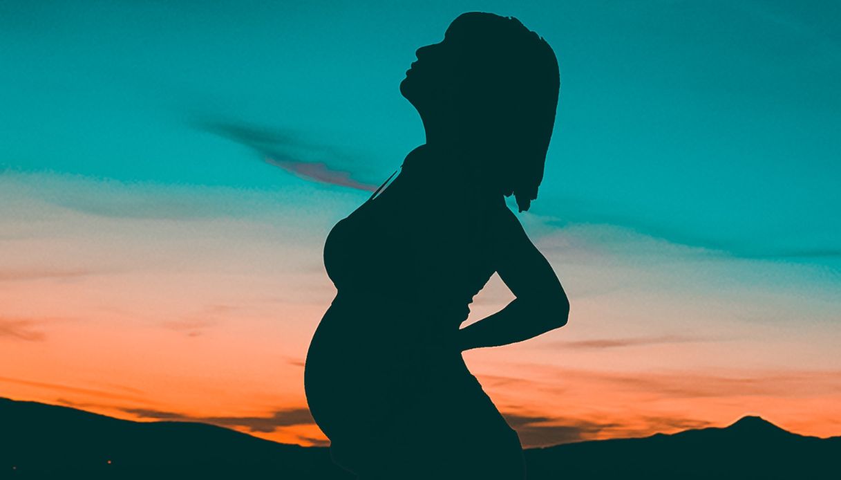 silhouette di donna incinta con capelli a caschetto e frangia con sfondo tramonto