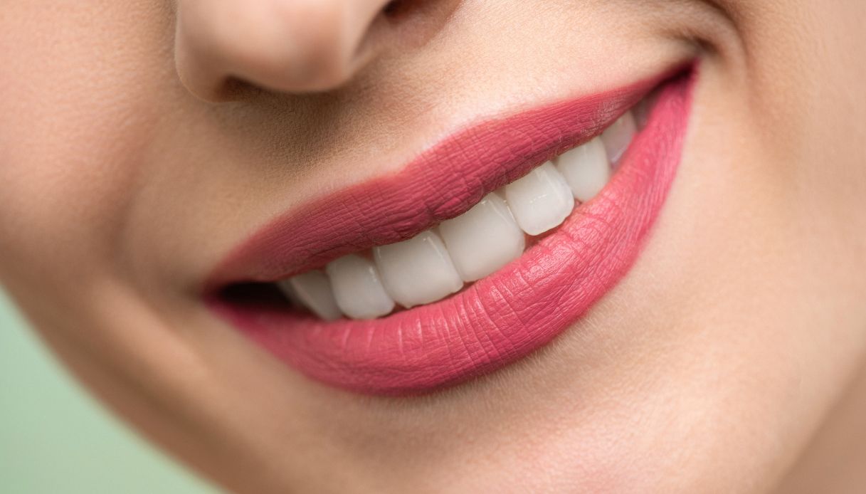 primo piano di labbra sorridenti con rossetto rosa opaco