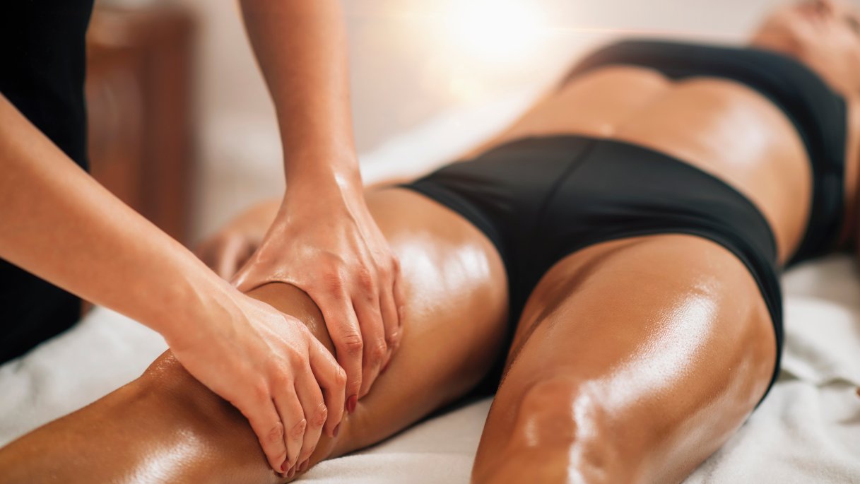 Una donna mentre si sottopone a un massaggio anticellulite e drenante alle cosce. Indossa intimo nero ed è sdraiata su un lettino medico