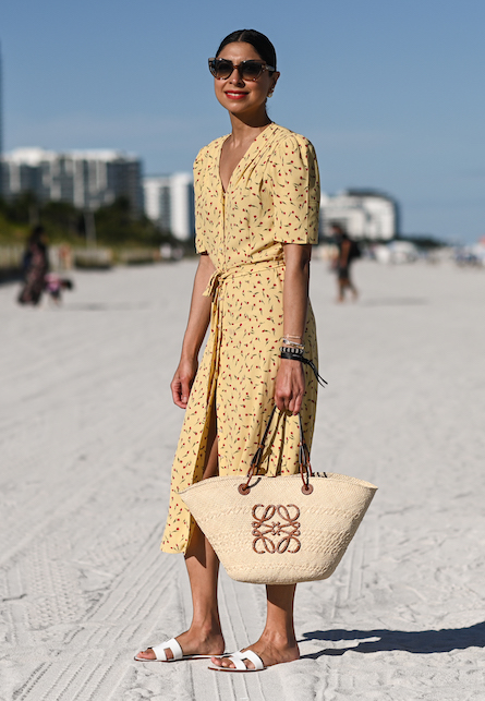 ragazza con abito giallo e borsa di paglia in spiaggia