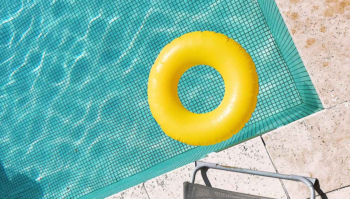 Gonfiabile giallo sopra una piscina con piastrelle a mosaico turchese