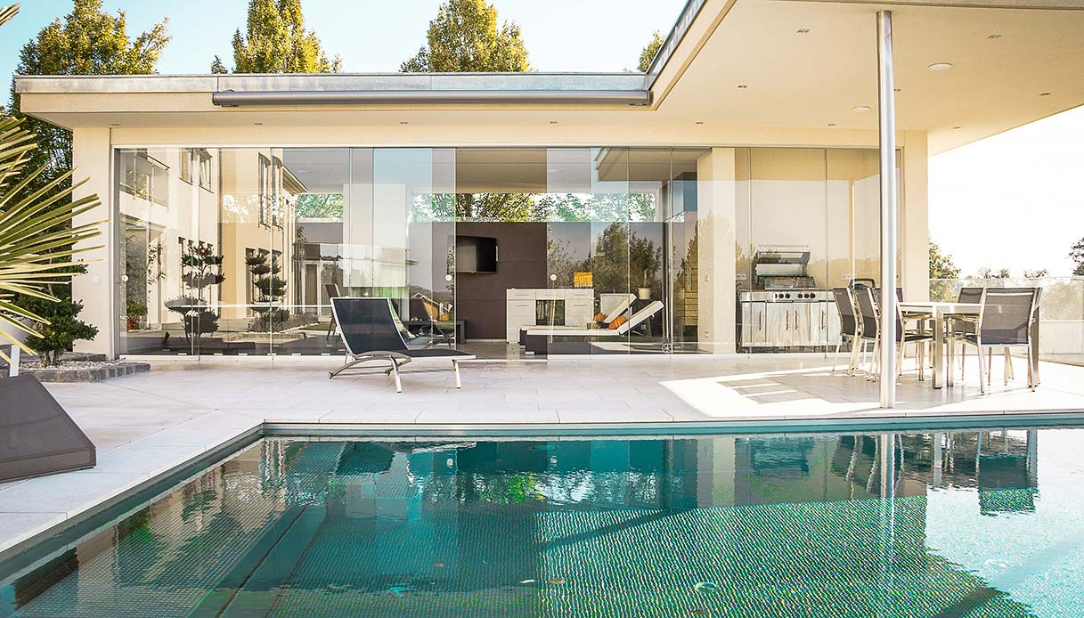 Piscina in una villa moderna con pareti in vetro e arredo outdoor