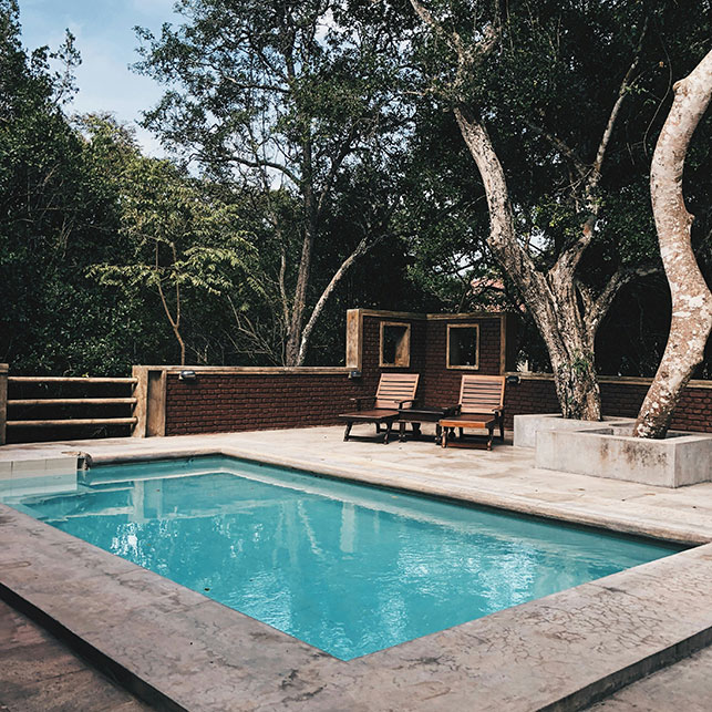 Piscina da esterno circondata da alberi e rivestimenti in legno e pietra