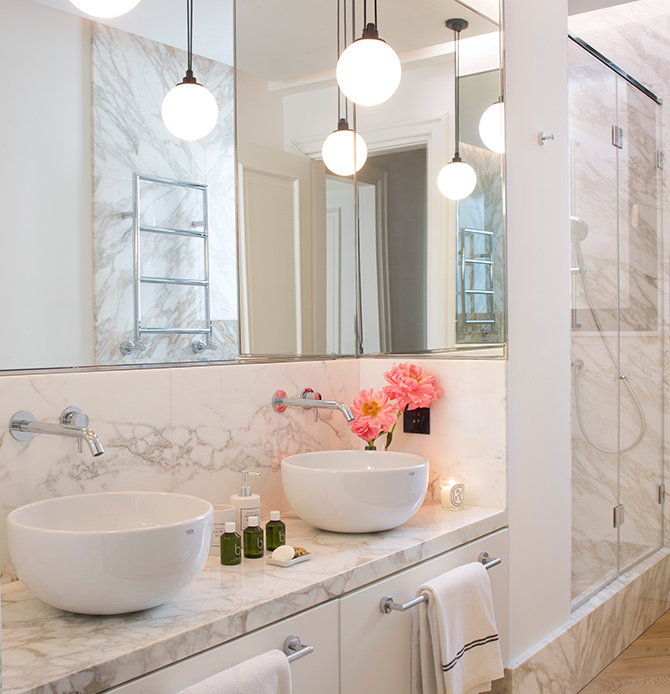 Bagno principale in marmo con doppio lavabo e specchio retroilluminato in un appartamento di design a Brera