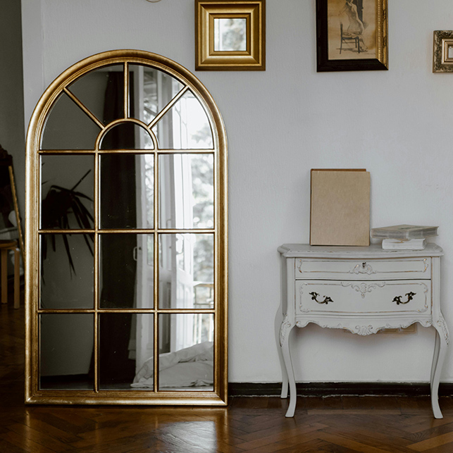 Grande specchio dorato e comò shabby chic in un interno romantico