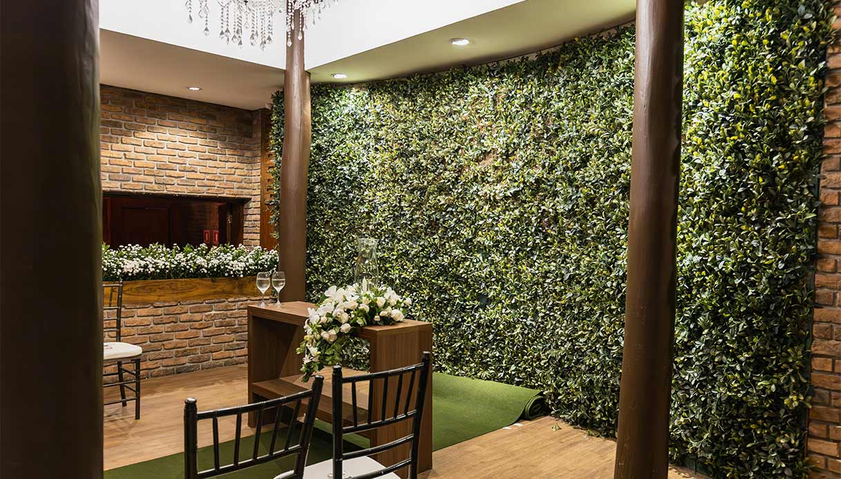 Parete verde verticale in sala eventi con arredi in legno e mattoni