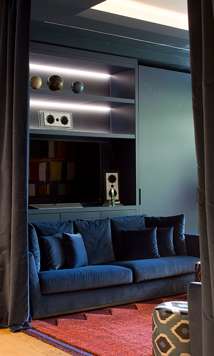 Salotto con divano in velluto blu e libreria integrata in appartamento di design a Brera