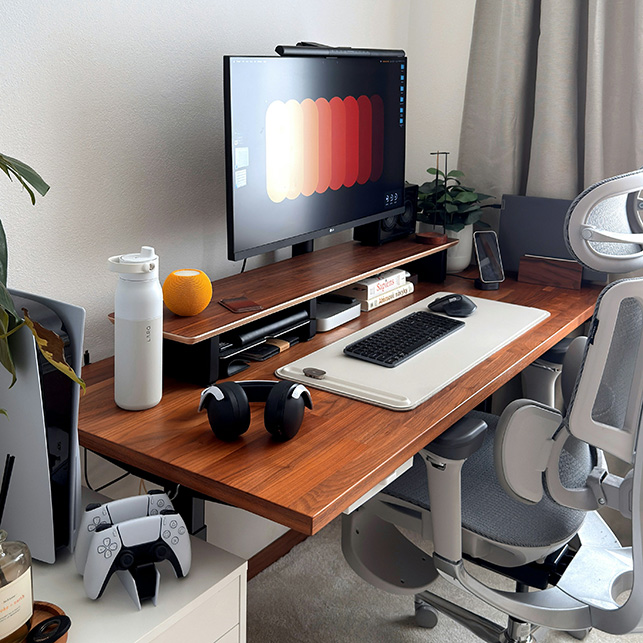 Postazione studio moderna con scrivania in legno, monitor widescreen, sedia ergonomica e accessori hi-tech.