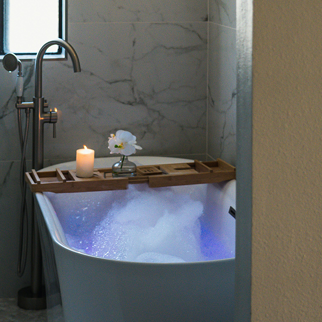 Candela accesa accanto a una vasca da bagno con atmosfera rilassante