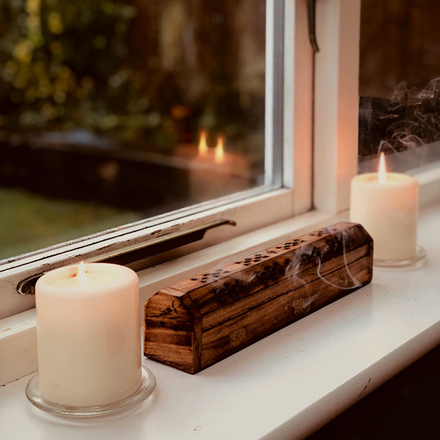 Due candele bianche accese su un davanzale con luce soffusa