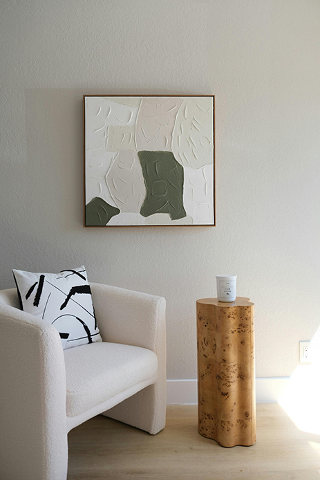 Poltrona chiara con tavolino in legno e quadro astratto dai toni neutri