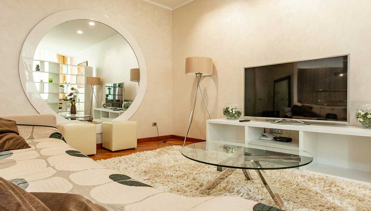 Soggiorno con specchio rotondo e arredi in tonalit&agrave; neutre