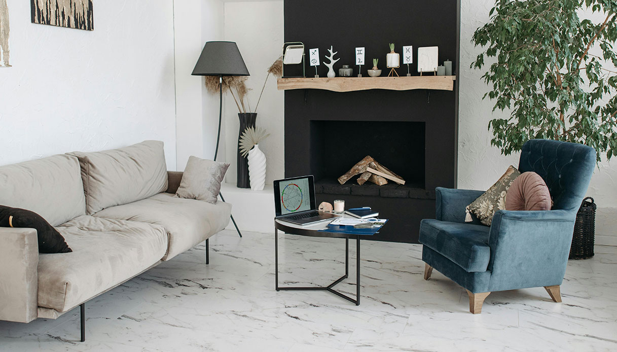 Poltrona blu in velluto vicino al camino in salotto moderno con arredi minimal