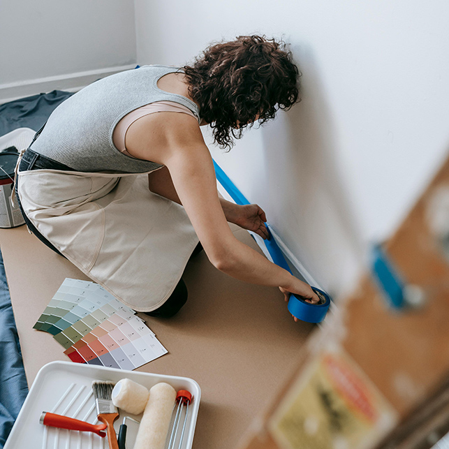 Donna applica nastro adesivo alle pareti per proteggere i bordi prima di tinteggiare