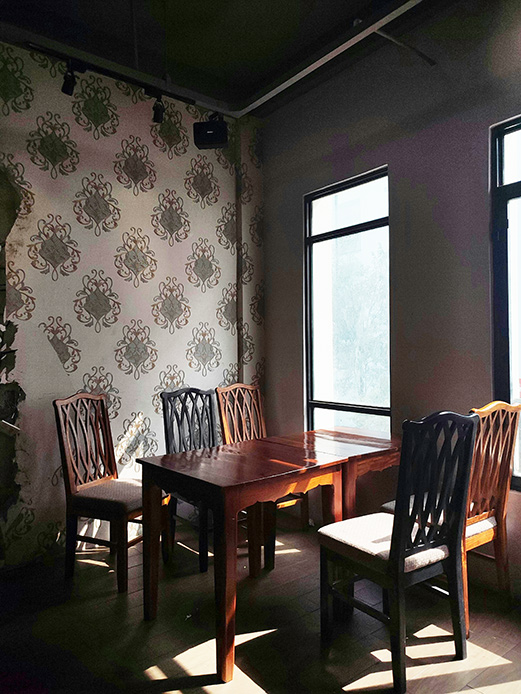 Sala da pranzo in legno con parete decorata e luce naturale dalle finestre