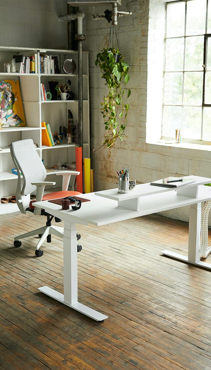 Studio moderno con scrivania regolabile in altezza e sedia ergonomica.