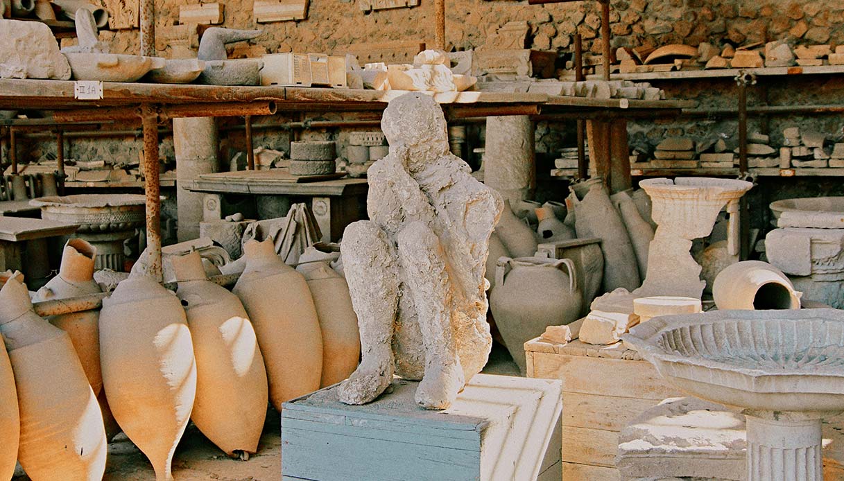 Collezione di anfore e una statua antica in esposizione, esempio di souvenir artigianali che possono valorizzare la casa