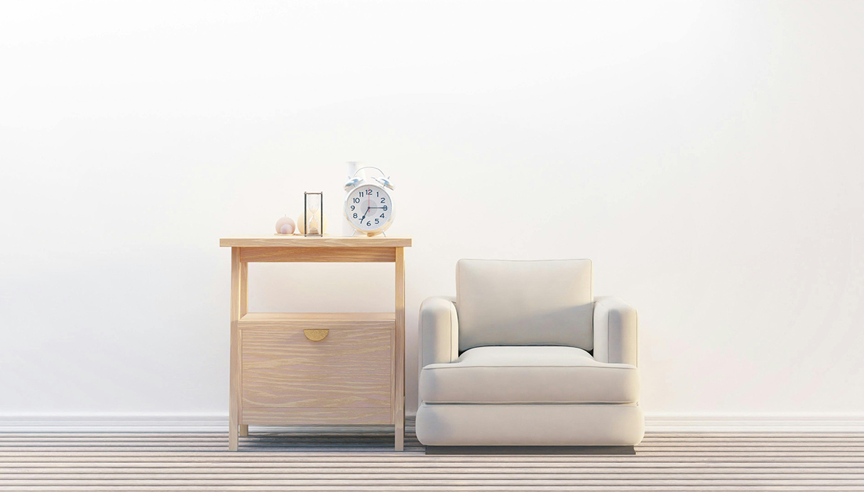 Angolo casa con poltrona chiara, mobile in legno e oggetti geometrici su sfondo bianco