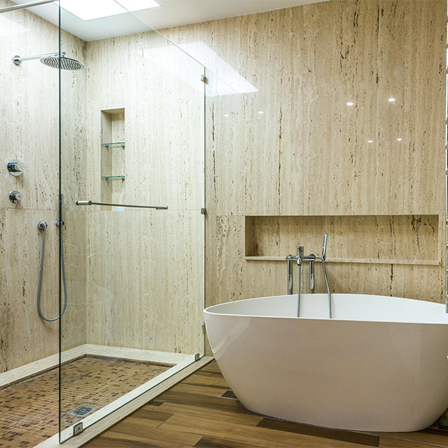 Bagno contemporaneo con pareti in marmo, doccia walk-in in cristallo e vasca bianca su pavimento in legno