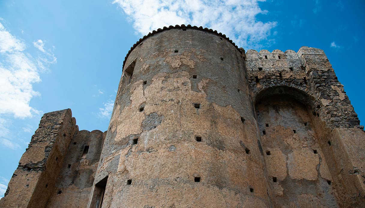 Torre circolare in pietra di un castello medievale italiano vista dal basso contro il cielo blu