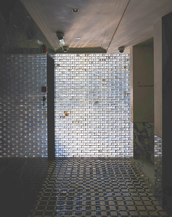 Corridoio moderno illuminato da parete in vetrocemento e pavimento a scacchi