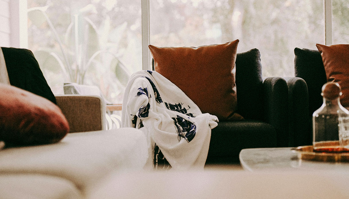 Divano con cuscini color terracotta e plaid bianco in un salotto luminoso