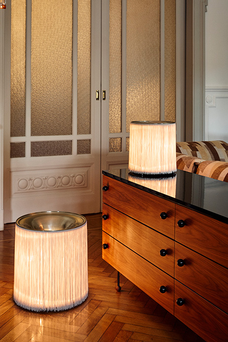 Lampade cilindriche con frange luminose in un interno elegante con parquet e arredi vintage