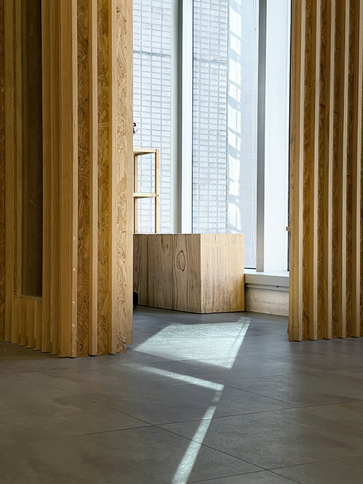 Interno moderno con pareti in legno e finestra in vetrocemento illuminata dal sole