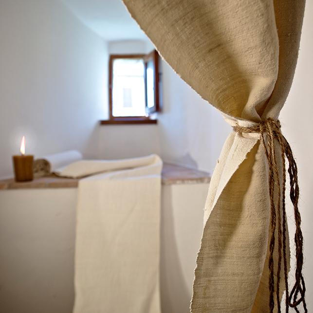Dettaglio di una finestra con tendaggi chiari e luce naturale all’interno della Torre della Botonta in Umbria