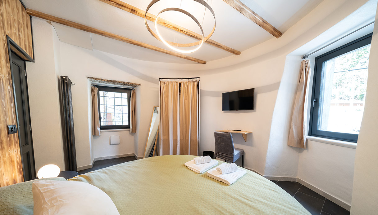 Interno della camera rotonda della Torre Malaspina, con letto tondo, travi a vista e finestre originali