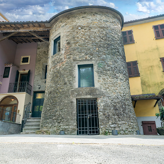 Facciata esterna in pietra della Torre Malaspina, affiancata da edifici moderni, nel borgo di Licciana Nardi