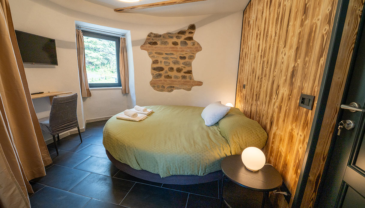 Interno della camera rotonda della Torre Malaspina, con letto tondo, travi a vista e finestre originali