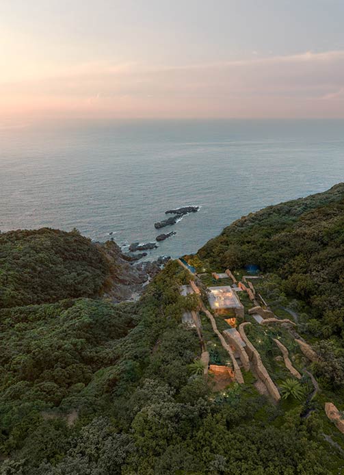 Veduta panoramica della villa affacciata sull’oceano al tramonto, circondata dalla vegetazione