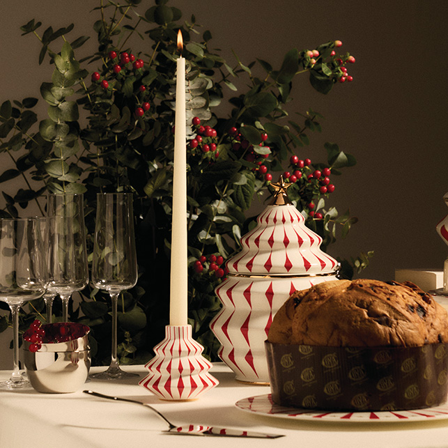 Candeliere natalizio bianco e rosso della collezione Delight accanto a panettone e calici.