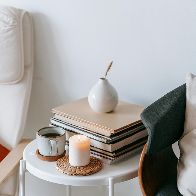 Tavolino con libri, candela e tazza accanto a seduta