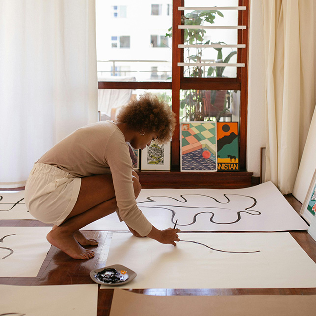 Persona che dipinge grandi fogli sul pavimento