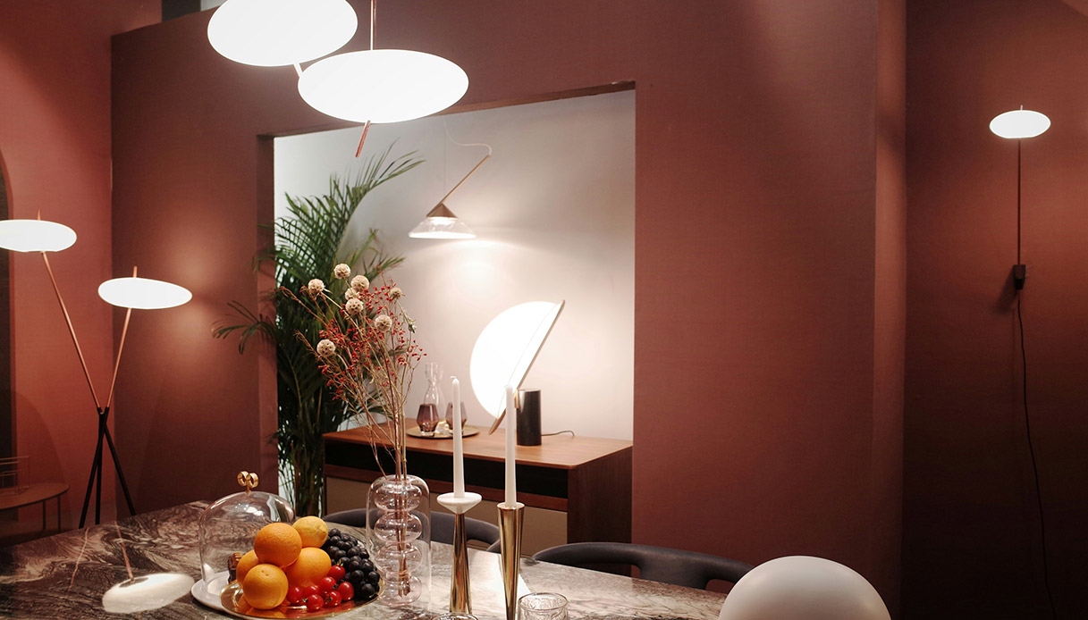 Varie lampade decorative illuminano un ambiente da pranzo con frutta e arredi moderni.