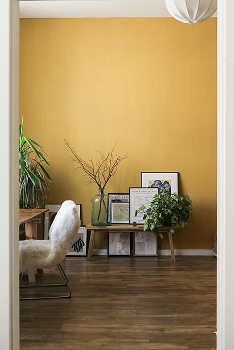 Parete color mustard yellow con piante e quadri appoggiati