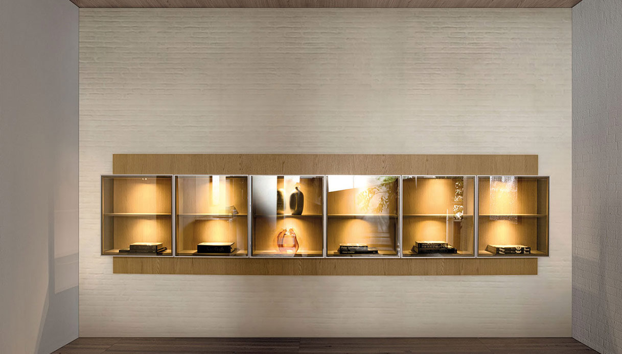 Credenza sospesa con vetrine illuminate e ripiani in legno su parete chiara